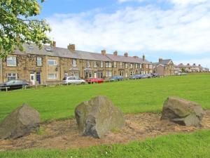 a field with rocks in front of a building at 3 Bed in Morpeth oc-cn137 in Amble