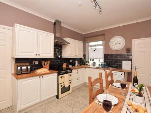a kitchen with white cabinets and a table and a clock at 3 Bed in Morpeth oc-cn137 in Amble