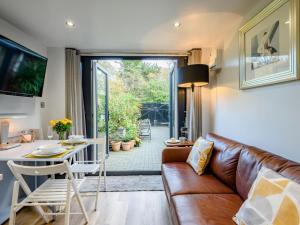a living room with a leather couch and a table and a dining room at 1 Bed in Christchurch oc-90444 in Highcliffe