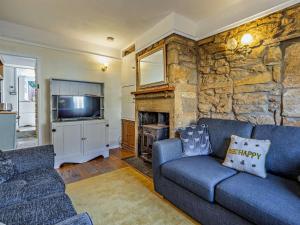 a living room with a blue couch and a stone wall at 3 Bed in Montacute oc-92227 in Montacute