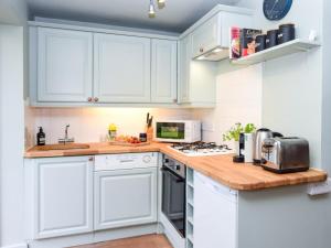 a kitchen with white cabinets and a wooden counter top at 1 Bed in Brockenhurst oc-78926 in Beaulieu +12 photos