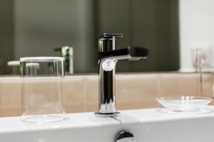 a bathroom sink with a faucet and two glasses at LaHouse Rome by Premium Suites Collection in Rome