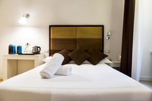 1 dormitorio con 1 cama grande con sábanas y almohadas blancas en LaHouse Rome by Premium Suites Collection, en Roma