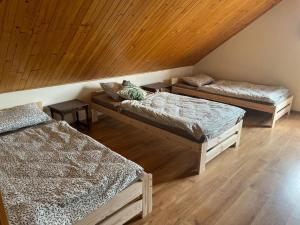 three beds in a room with a wooden ceiling at Dom Acapulco in Kromszewice