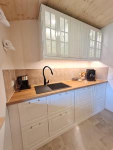 a kitchen with white cabinets and a sink at CHIEMSEE MOUNTAIN LODGE - adults only - Eleganz auf 95qm - Traumblick - XL-Balkon - Privatsphäre in Bernau am Chiemsee +38 photos