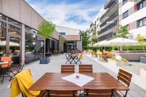 eine Terrasse mit einem Holztisch und Stühlen in der Unterkunft Best Western Hotel Kaiserslautern in Kaiserslautern