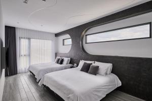 two beds in a hotel room with a window at 藤夏日光 in Weiqian