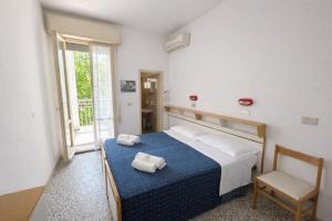 a bedroom with a bed and a chair and a window at Camere Capinera in Cesenatico