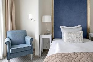 a bedroom with a bed and a blue chair at Dorint Parkhotel Meißen in Meißen +150 photos