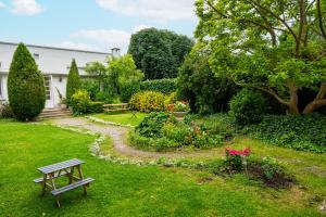 ein Garten mit einer Bank und Blumen im Gras in der Unterkunft Hotel Joly in Armentières