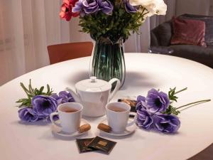 a table with two cups of coffee and a vase of flowers at LEONI DI COLLALTO PALACE in Treviso