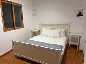a bed with white sheets and pillows in a bedroom at Ático centro Benicasim in Benicàssim