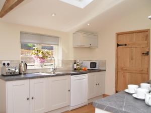 a kitchen with white cabinets and a sink and a window at 3 Bed in Bristol oc-58129 in Burrington +12 photos