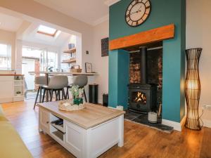 a living room with a fireplace and a clock on the wall at Hill View Cottage in Ashbourne