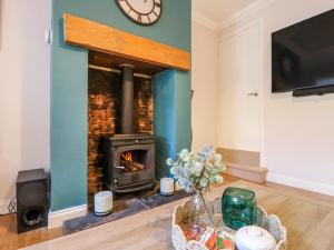 a living room with a fireplace with a clock on the wall at Hill View Cottage in Ashbourne