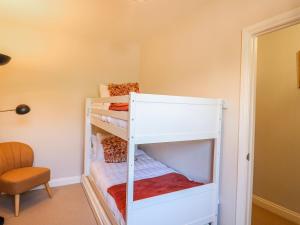 a white bunk bed in a room with a chair at Hill View Cottage in Ashbourne