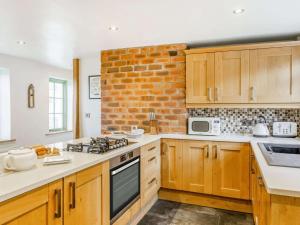 a kitchen with wooden cabinets and a brick wall at 3 Bed in Keighley oc-89528 in Haworth +11 photos