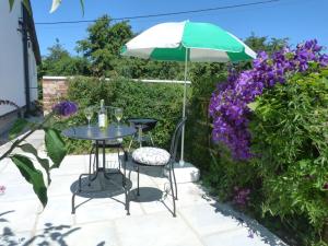 a table and two chairs with an umbrella and purple flowers at 1 Bed in Taunton oc-49569 in North Curry