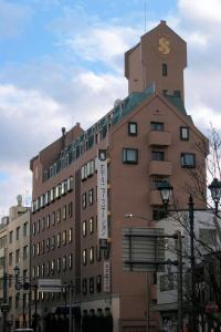 a building with a clock tower on top of it at Hotel New Station in Matsumoto