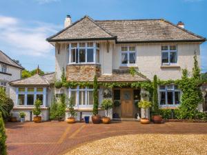 a large white house with potted plants on a driveway at Bradleigh Lodge in St Austell