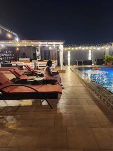 a person sitting next to a swimming pool at night at FortExcel Hotels & Suites in Odogun