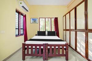 a bedroom with a bed in a room with windows at Hotel O Nakshathra Inn in Kazhakuttam