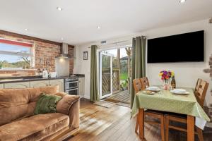 a living room with a couch and a table at Ffynnonlwyd Cottage - rural holiday cottage with hot tub in Llangynin +20 photos