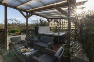 a patio with a hot tub and a table and chairs at Ffynnonlwyd Cottage - rural holiday cottage with hot tub in Llangynin