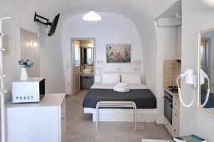 a small white bedroom with a bed and a table at Yposkafo Suites - Private Studio - Santorini in Fira