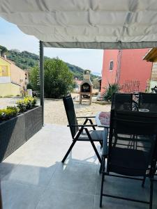 a patio with two chairs and a table and an umbrella at Apartment ADEPTO in Sveti Jakov