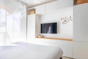 a bedroom with a bed and a tv on a wall at La Pomponnette du Bassin in Arcachon