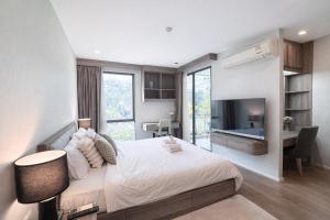 a bedroom with a large bed with a desk and a bed sidx sidx sidx sidx at Spacious 2BR Condo with 2 Balconies in Sukhumvit16 in Bangkok +13 photos