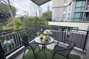 a table with two chairs and a bottle of wine on a balcony at Spacious 2BR Condo with 2 Balconies in Sukhumvit16 in Bangkok