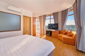a bedroom with a bed and a couch and a flat screen tv at Cát Tường Hotel in Da Lat