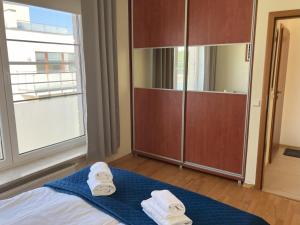 a bedroom with towels on a bed with a large window at Aquamarina Turkus Apartament 253 in Międzyzdroje