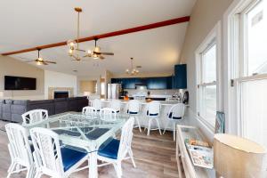 a dining room and kitchen with a glass table and white chairs at Rylander-Timmerman House OBX in Nags Head