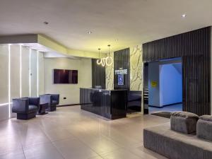 a lobby with chairs and a bar in a building at Peregrine Hotel Jos in Jos