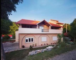 a pink house with a red roof at Apartments Velebit house in Biljevine