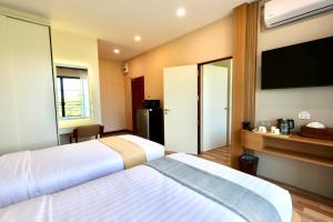 a hotel room with two beds and a flat screen tv at KL Dawarika Mali Hotel in Ban Tai