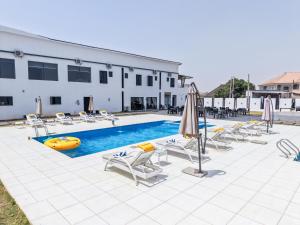 a pool with chairs and umbrellas next to a building at Peregrine Hotel Jos in Jos +13 photos