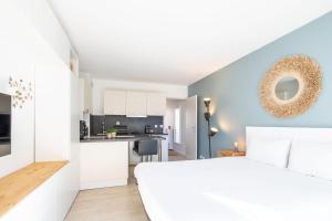 a bedroom with a white bed and a kitchen at La Pomponnette du Bassin in Arcachon