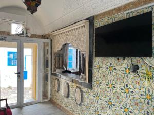 a flat screen tv on a wall with flowers on it at Hôtel Bou Fares in Sidi Bou Saïd