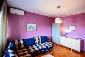 ein Wohnzimmer mit lilafarbenen Wänden und einem Sofa in der Unterkunft Marina Bay Apartment in Zadar