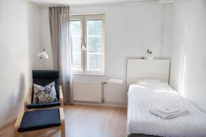 a bedroom with a bed and a chair and a window at Strömbäcks Vandrarhem in Umeå