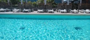 a pool of blue water with white chairs and chairs at Camping Continental in Mandello del Lario