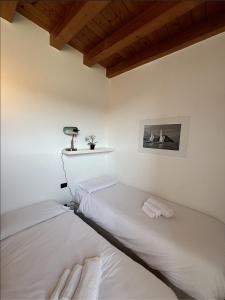 two beds in a room with white walls and wooden ceilings at COZY LAKE COMO APARTMENTS in Valmadrera +38 photos