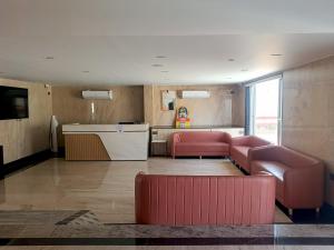 a living room with two red couches and a kitchen at Crystal Residency - Panjappur Trichy in Pūngudi