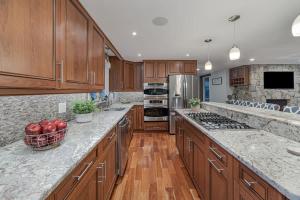 a kitchen with wooden cabinets and granite counter tops at Beachside family POOLSPAOPEN20thAPril in Barnstable