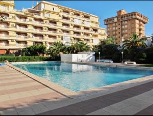 a swimming pool in front of a large building at Apto 1 Hab, Terraza & Piscina, 5 min Playa in Playa de Gandia