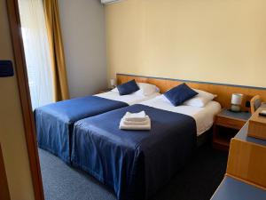 two beds in a hotel room with towels on them at Tamaris Rooms in Zadar